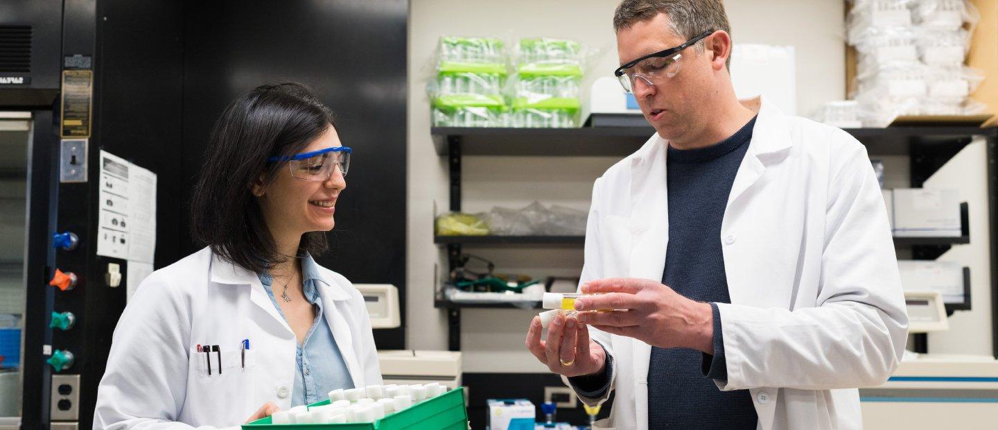 一个男人和一个女人，穿着实验室工作服，在实验室里看着小瓶.