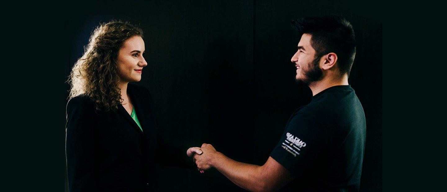 man and woman in black shaking hands against a black background