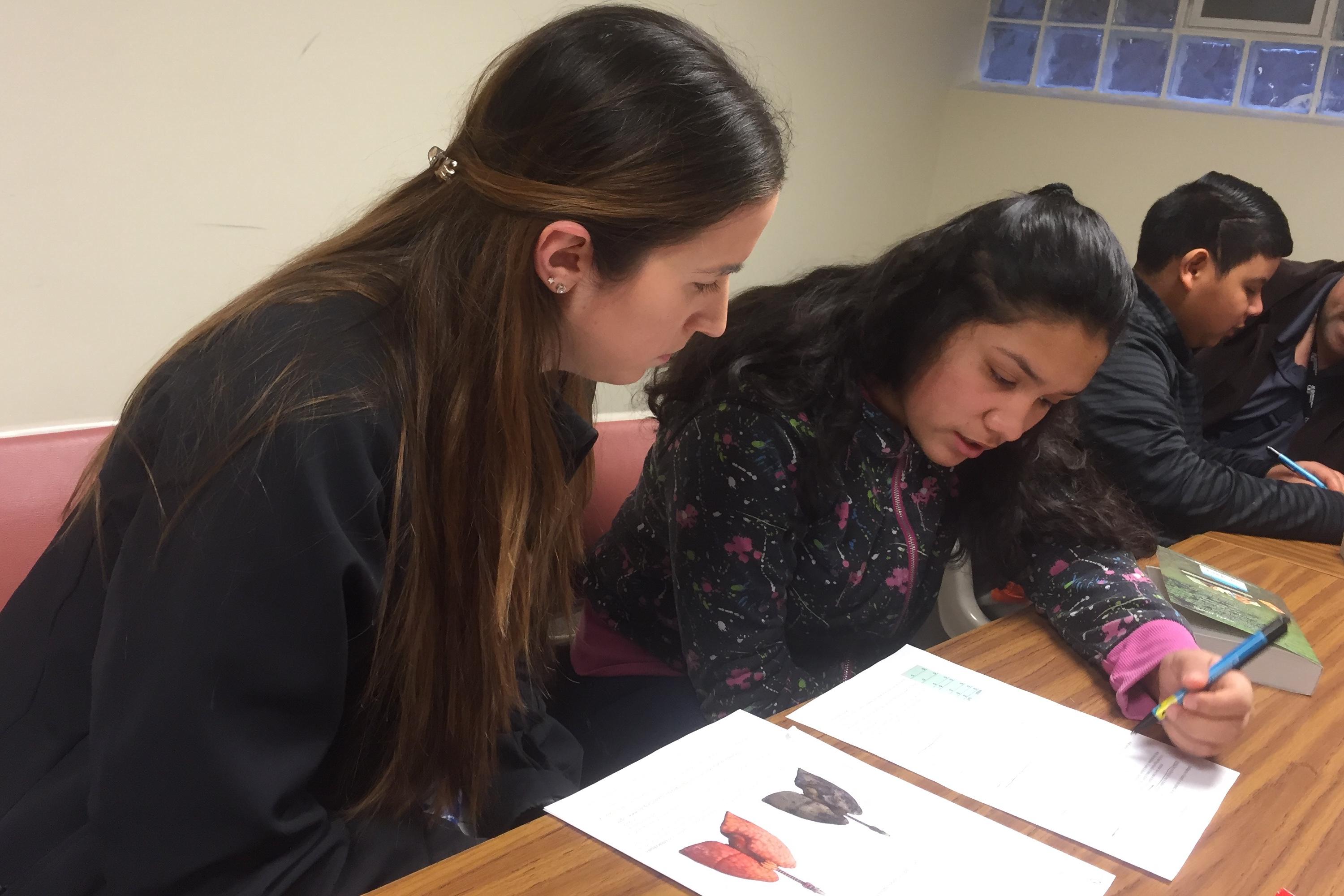 OUWB student helps high school student with her homework.