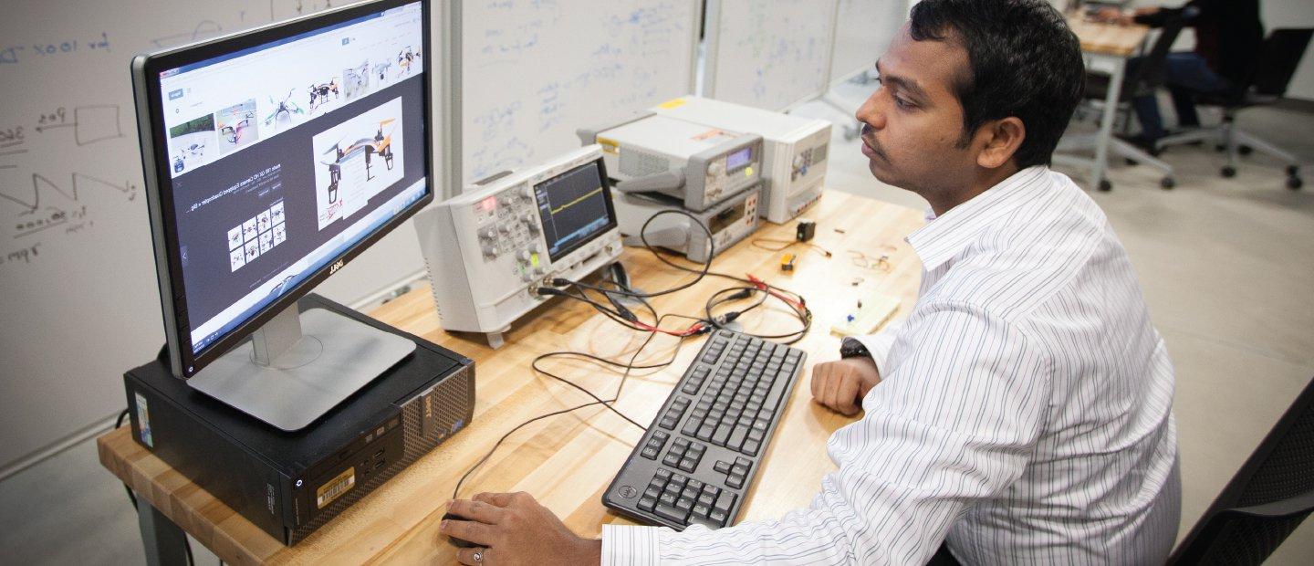 一个人坐在电脑前，屏幕上显示着机器人的图像